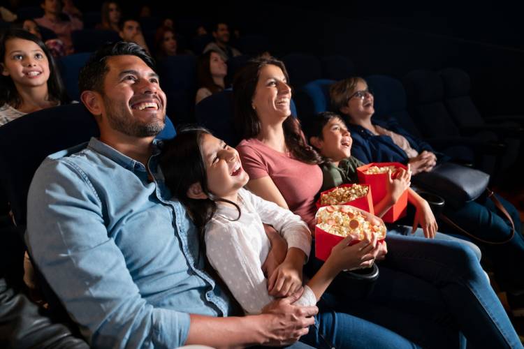 family smiling in a movie theater